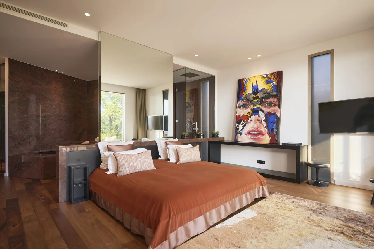 Suite avec couvre-lit orangé, salle de bain marbre brun attenante