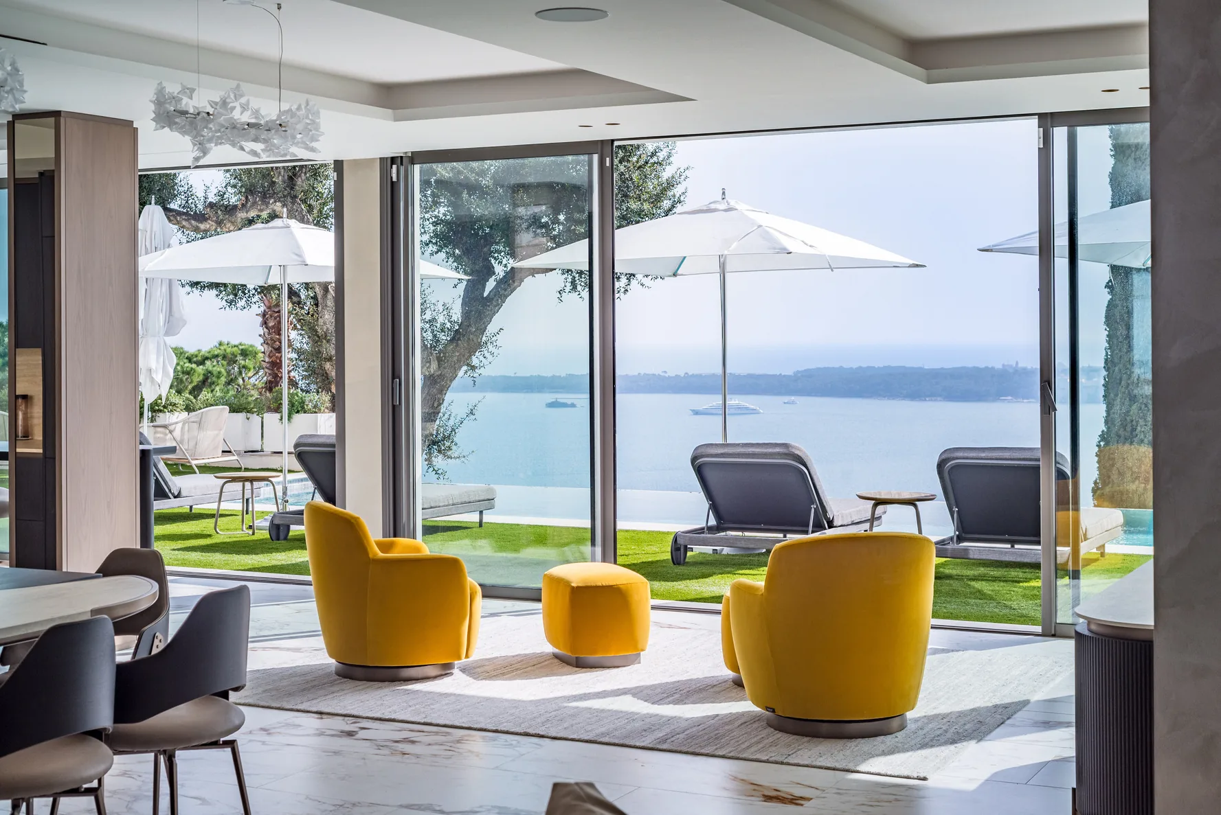 Salon d’appoint avec fauteuils jaunes design et baies vitrées sur la mer