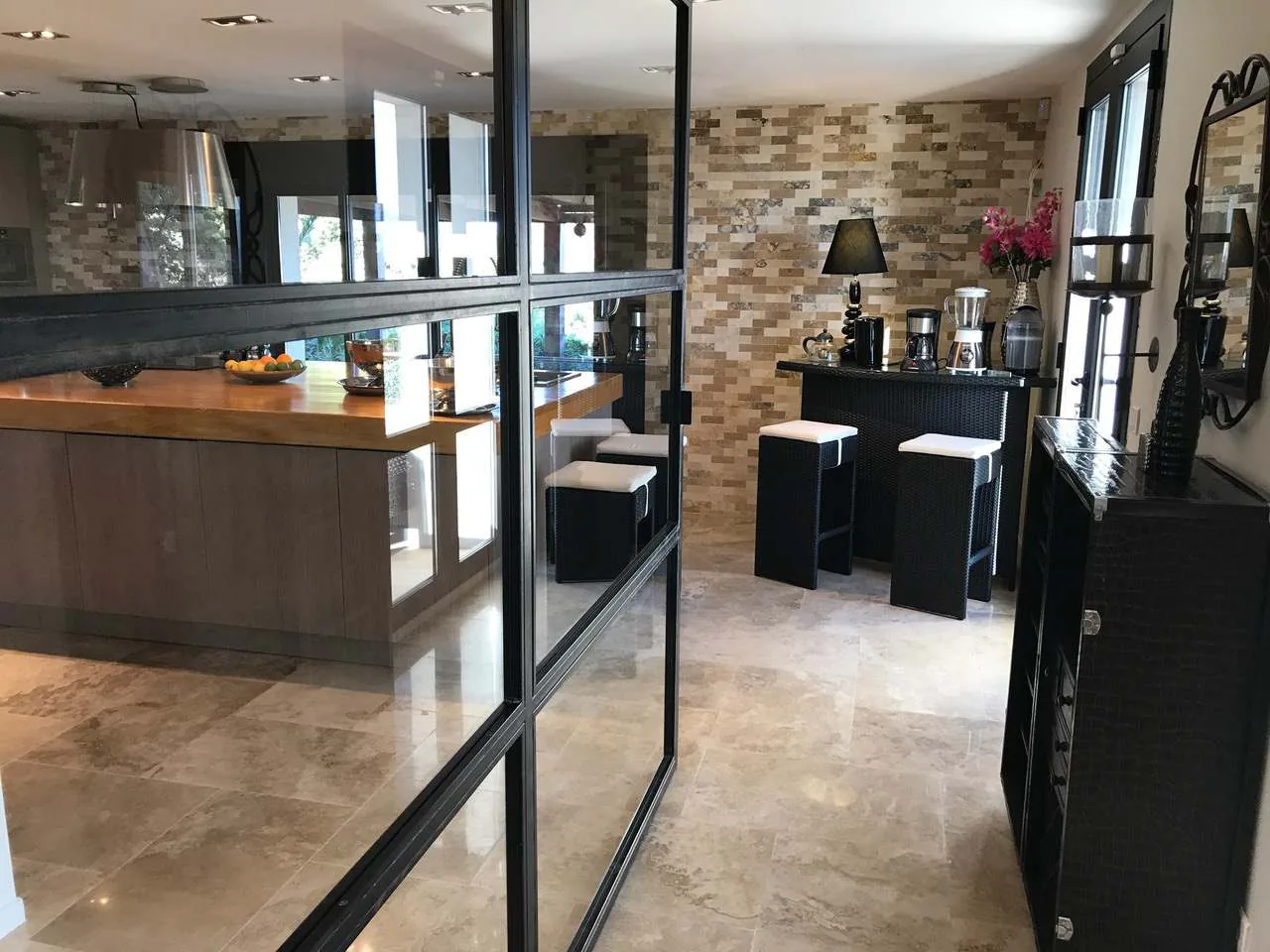 Cuisine ouverte avec verriere atelier en acier noir et bar a cafe en pierre travertin