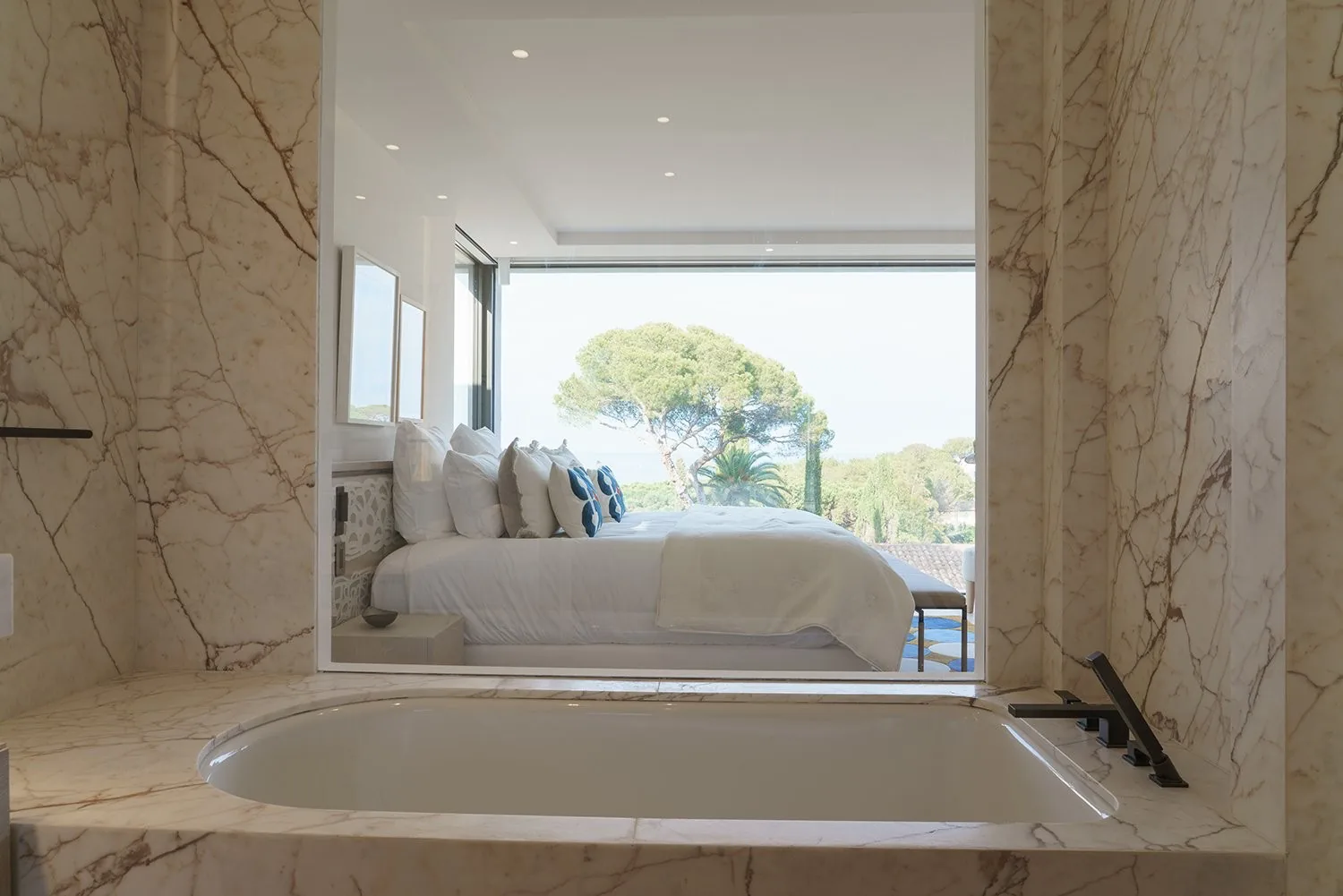 Salle de bain marbre avec ouverture vue mer sur la chambre