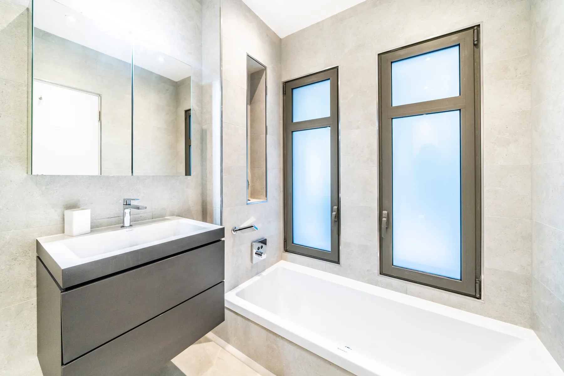 Salle de bain grise avec douche italienne et miroir rond chromé
