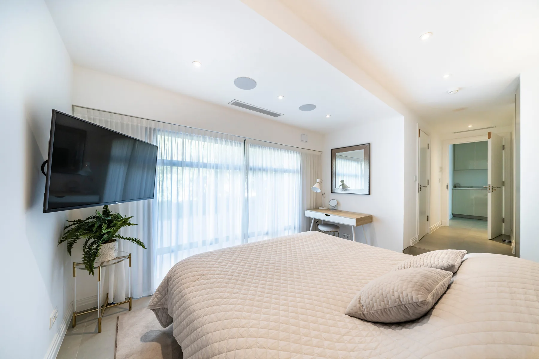 Chambre avec fauteuil vert d'eau, lit double et grande baie lumineuse