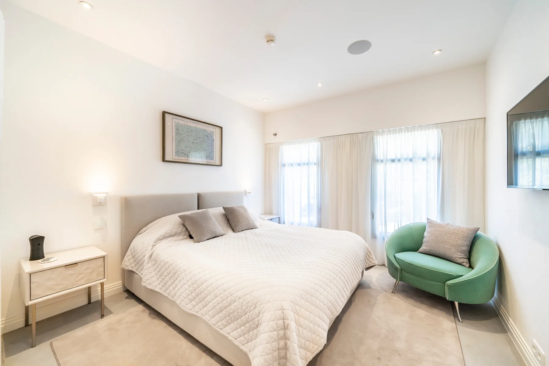 Chambre queen avec TV mural, ambiance neutre et accès couloir