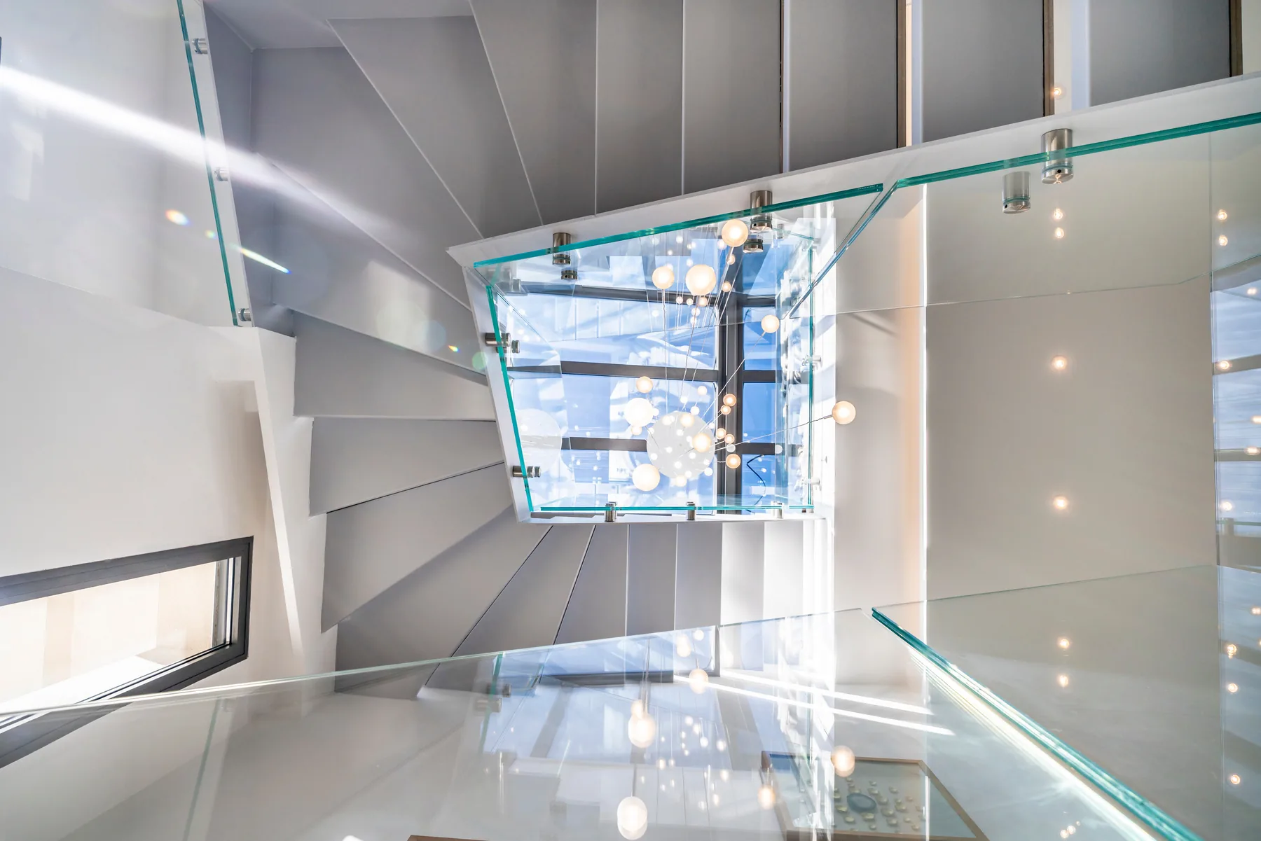 Escalier sculptural avec garde-corps verre et suspension cristal