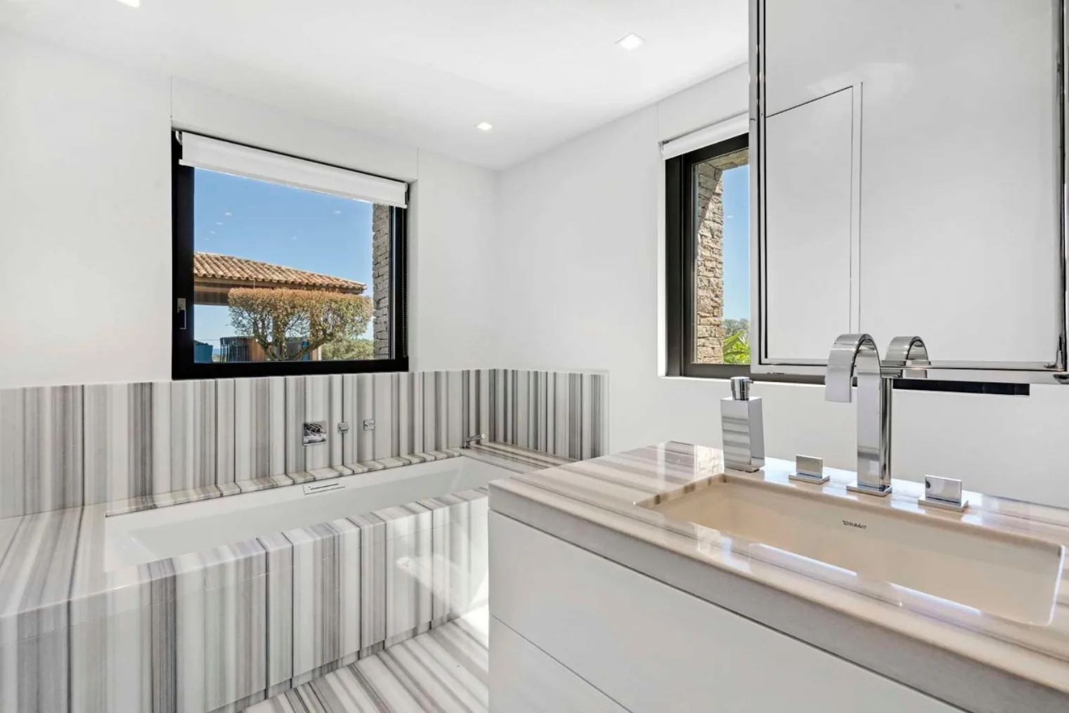 Salle de bain blanche lumineuse avec baies