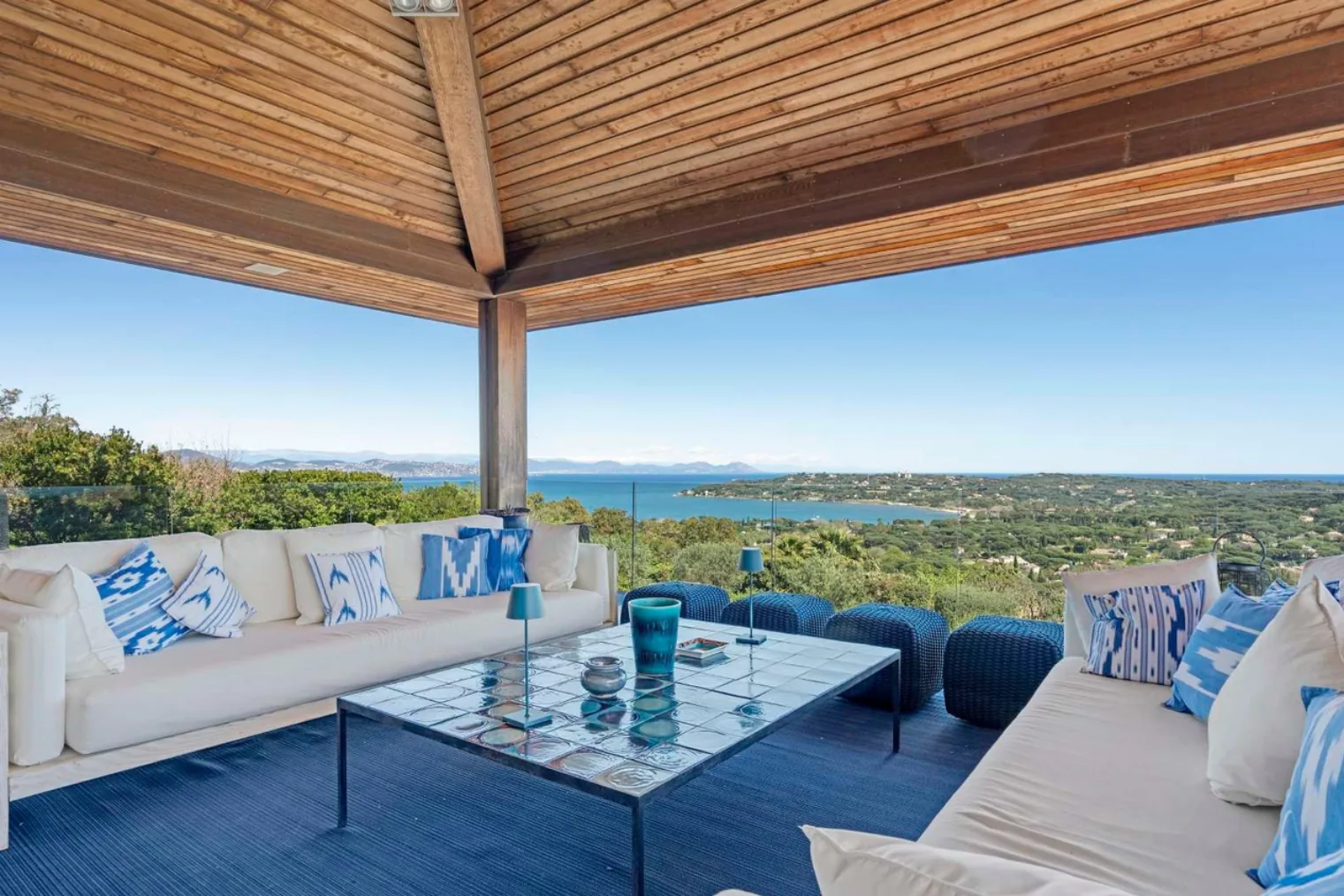 Terrasse couverte avec salons coussins ikat bleus vue mer