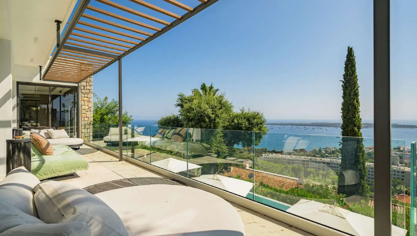 Terrasse couverte sous pergola avec lounges et vue mer