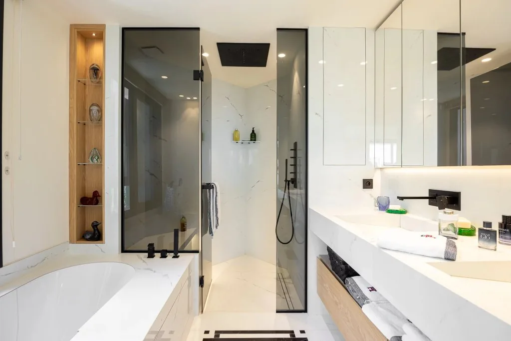 Salle de bain marbre avec douche italienne verre, baignoire et niche bois