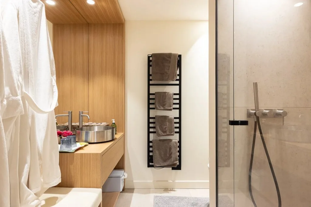 Salle de bain bois clair avec porte-serviettes design et douche italienne