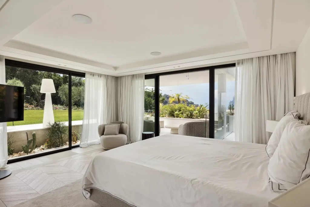 Chambre avec lit double et baie vitrée sur jardin et terrasse