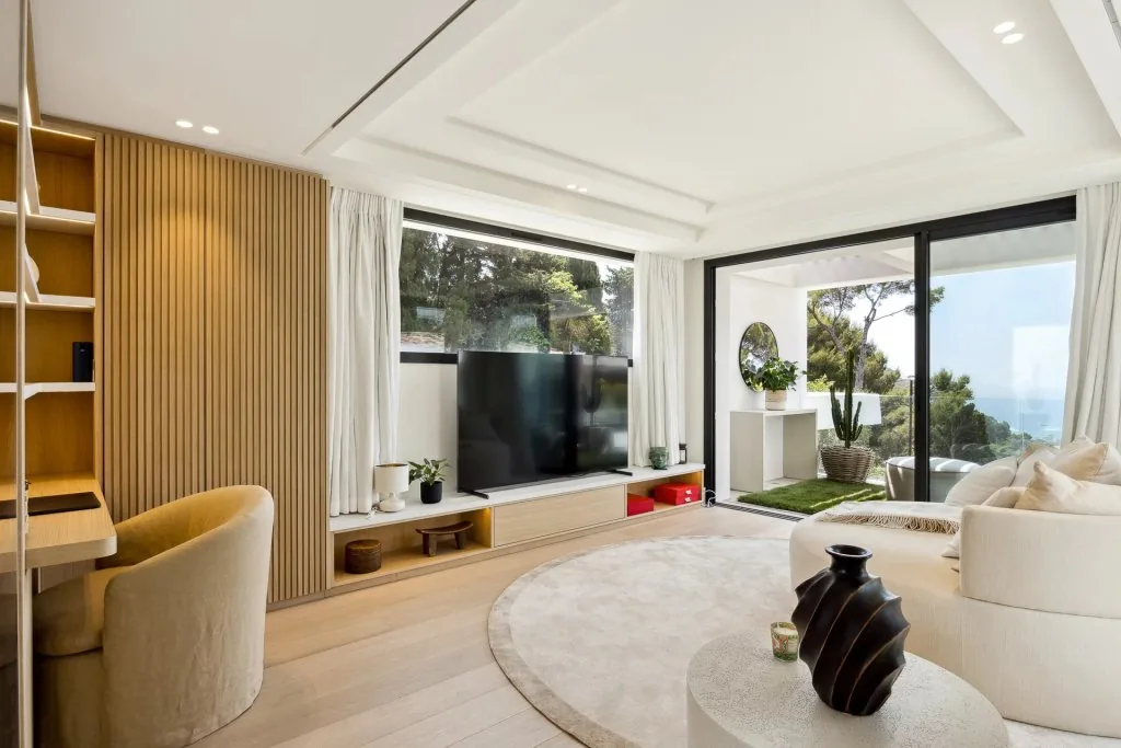 Chambre avec TV grand format, panneaux bois clair et accès terrasse
