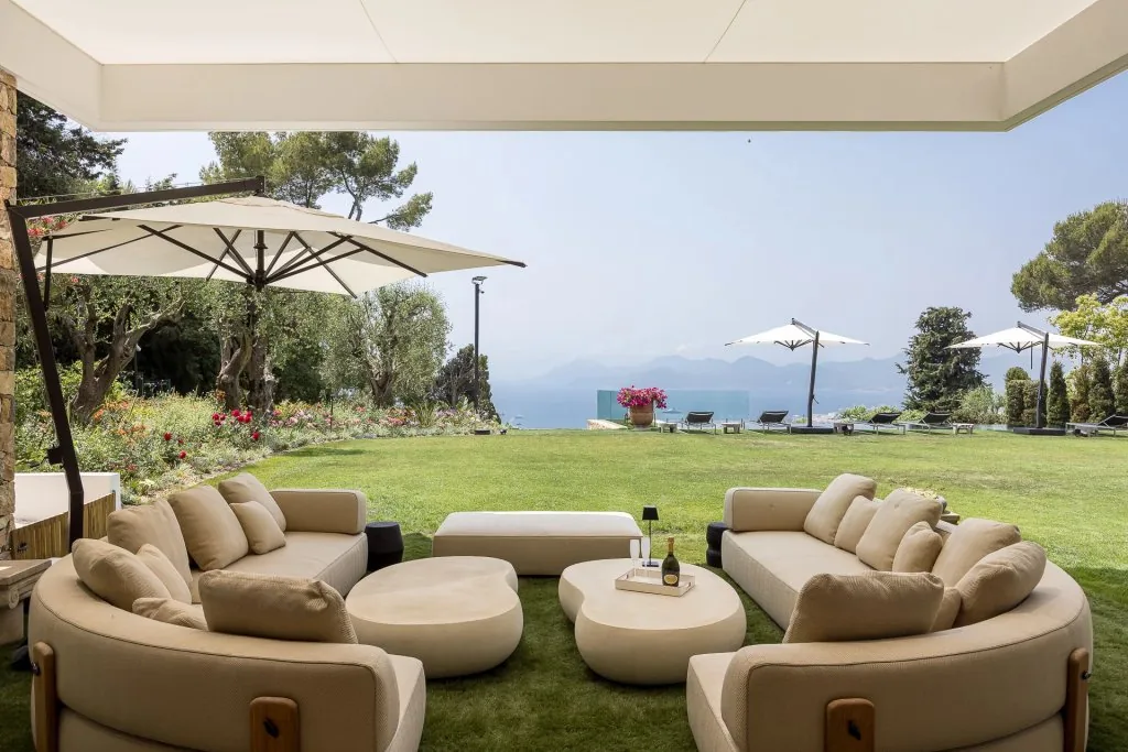 Salon extérieur lounge sous parasols avec vue mer et jardin paysagé