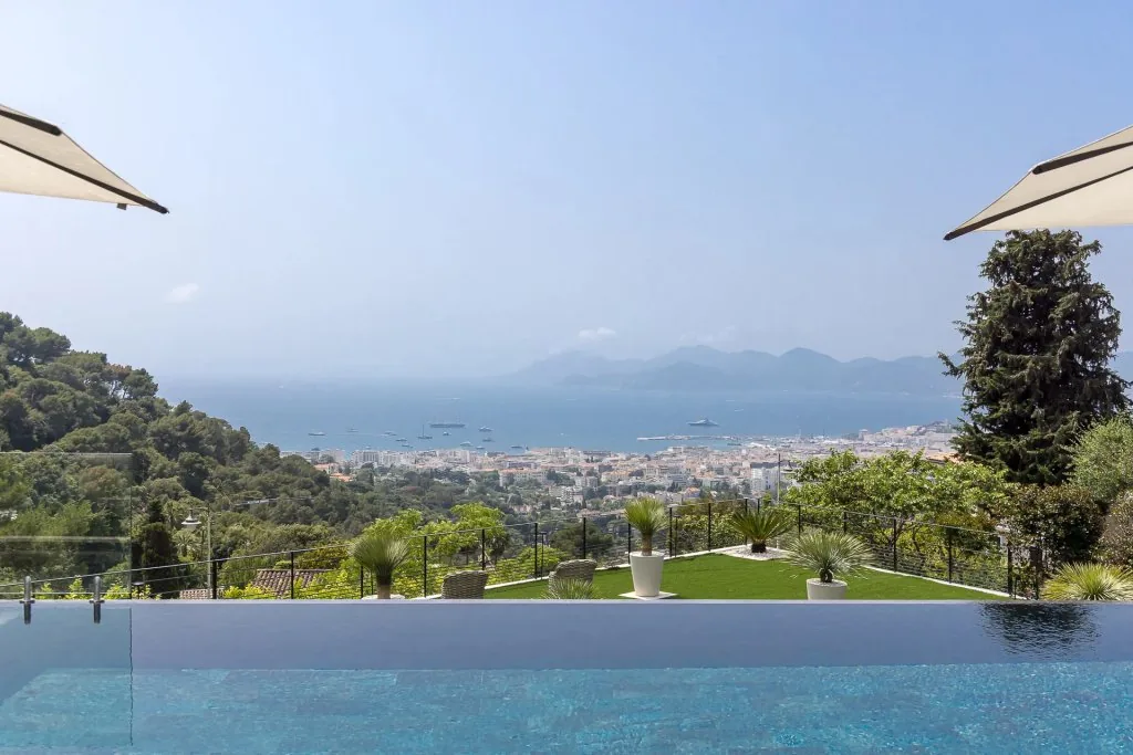 Piscine à débordement, bains de soleil sous parasols et baie de Cannes