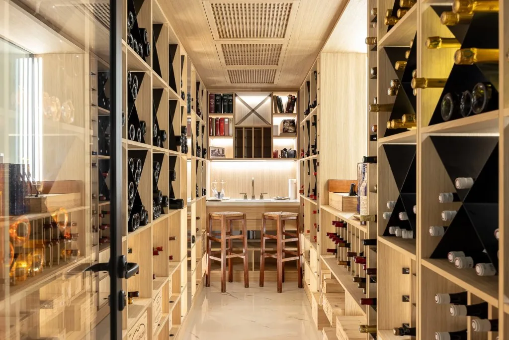 Cave à vins bois clair avec rangements éclairés et coin dégustation