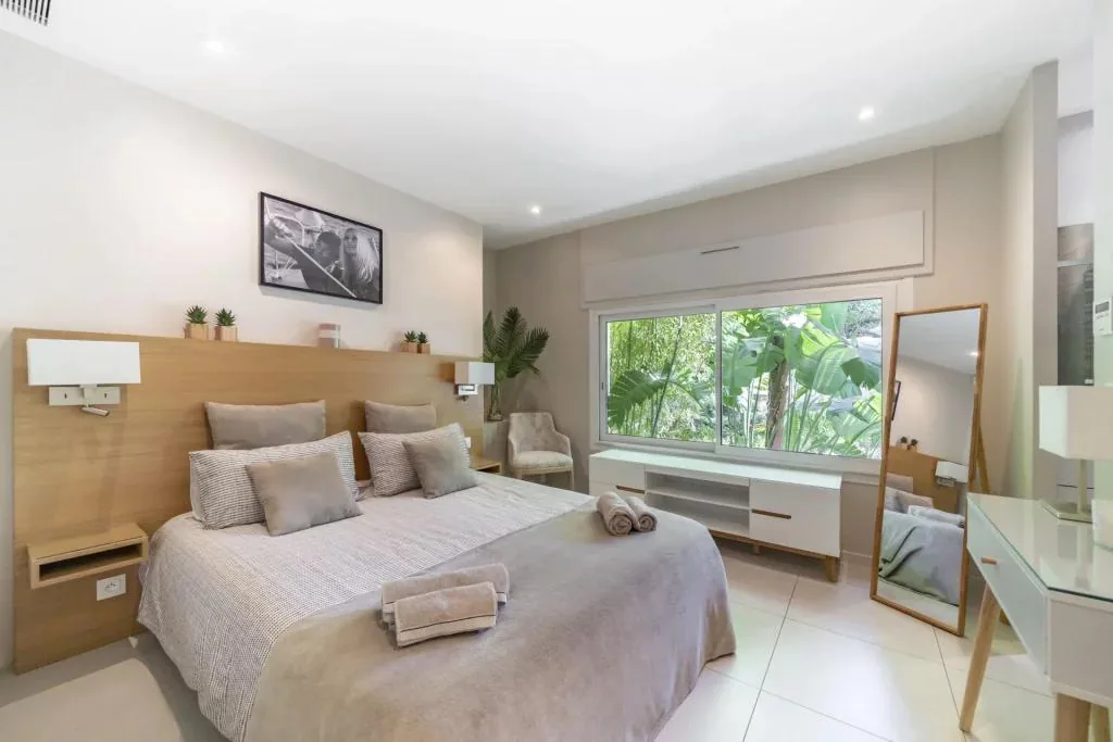 Chambre tons clairs bois et lin avec vue jardin tropical