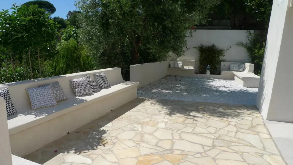 Terrasse pierre dallée avec banquettes et coin lecture ombragé