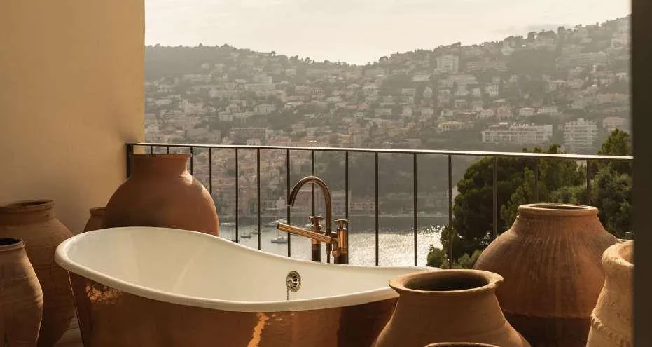 Bains de soleil sous parasols en pierre travertin au bord de la piscine